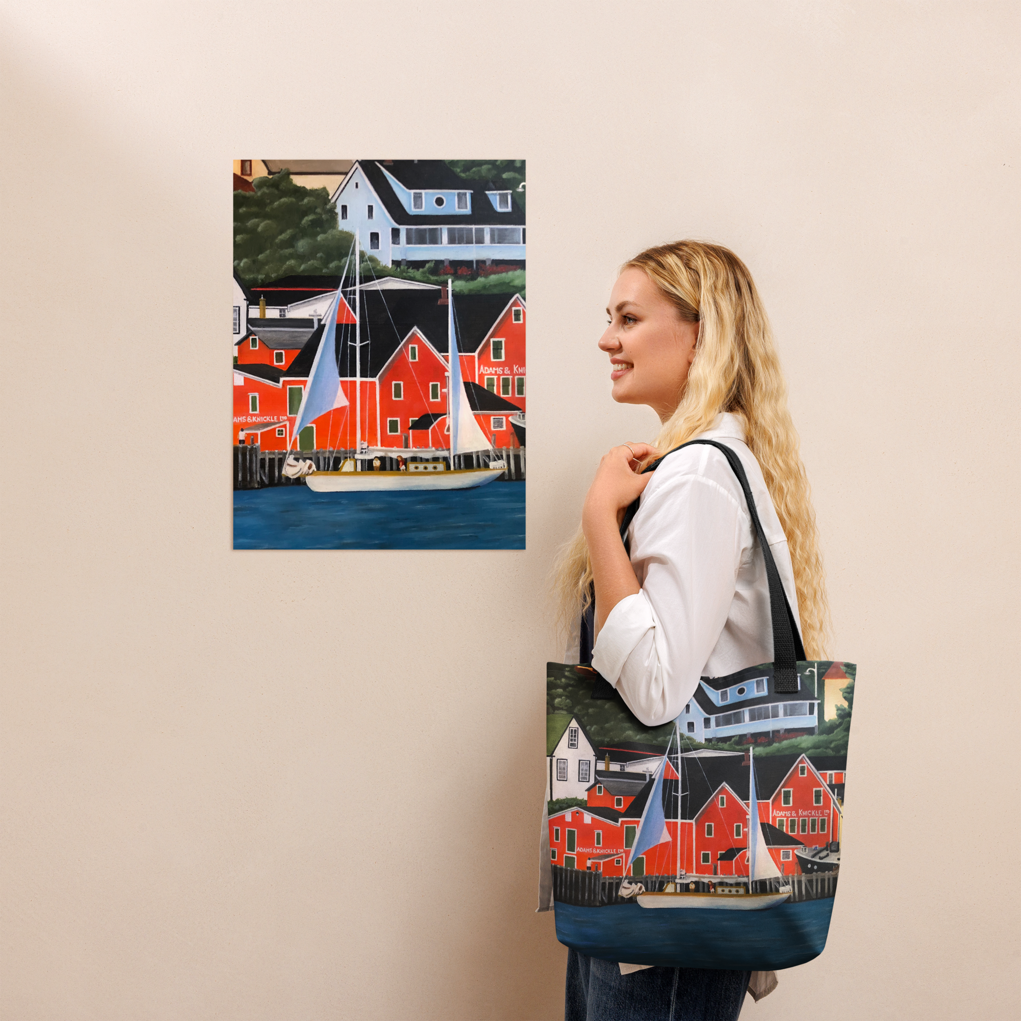 Woman holding a tote bag which is decorated with a Lunenberg harbor painting.